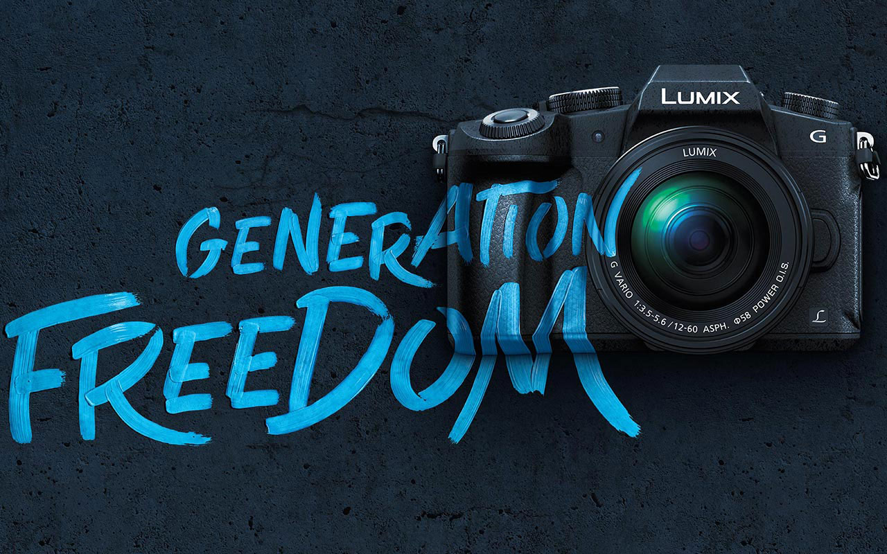 Kamera mit „LUMIX“-Schriftzug vor dunkler Betonwand, darüber großer blauer Graffiti-Schriftzug „GENERATiON FREEDUM“.